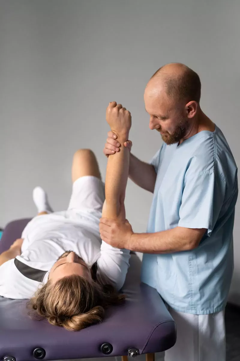 Ein Physiotherapeut macht Krankengymnastik mit einem Patienten. Es ist eine Behandlungsart in der Physiotherapie.